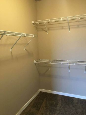 a walk in closet in a bedroom plus den unit at the abbey at stone oak in at Courtyard Apartments, Moorhead, MN
